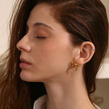 Load image into Gallery viewer, Close-up of a woman wearing a gold earring with a neutral background