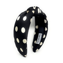 Load image into Gallery viewer, Black headband with white polka dots, featuring a twisted knot design. A label inside reads "Twine and Love." The style is stylish and playful.