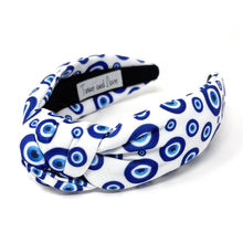 Load image into Gallery viewer, White and blue headband with a knot design featuring an evil eye pattern. The design is vibrant and playful, giving a trendy and stylish feel.