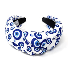 Load image into Gallery viewer, White and blue headband with a knot design featuring an evil eye pattern. The design is vibrant and playful, giving a trendy and stylish feel.