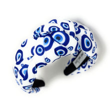 Load image into Gallery viewer, White and blue headband with a knot design featuring an evil eye pattern. The design is vibrant and playful, giving a trendy and stylish feel.