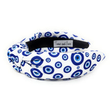 Load image into Gallery viewer, White and blue headband with a knot design featuring an evil eye pattern. The design is vibrant and playful, giving a trendy and stylish feel.