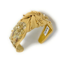 Load image into Gallery viewer, Golden padded headband adorned with intricate floral embroidery and pearl accents, exuding elegance and sophistication against a plain backdrop.