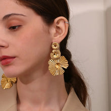 Load image into Gallery viewer, Close-up of a woman wearing gold earrings with a neutral background