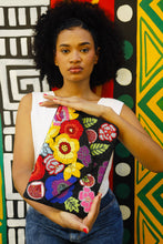 Load image into Gallery viewer, Woman holding a colorful beaded clutch against a patterned background