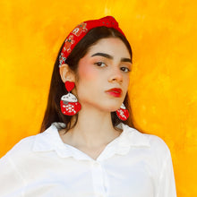 Load image into Gallery viewer, Woman wearing a white shirt, hot cocoa design earrings, red headband, and blue jeans against a yellow background