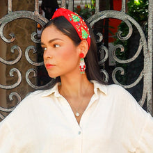 Load image into Gallery viewer, Woman in a white blouse and blue jeans standing in front of a decorative metal gate.
