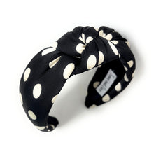 Load image into Gallery viewer, Black headband with white polka dots, featuring a twisted knot design. A label inside reads "Twine and Love." The style is stylish and playful.
