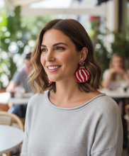 Load image into Gallery viewer, Woman wearing red and white striped earrings in an outdoor setting