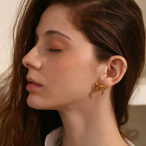 Close-up of a woman wearing a gold earring with a neutral background