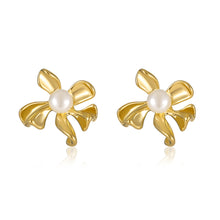 Load image into Gallery viewer, A pair of gold flower-shaped stud earrings with a white faux-pearl center, displayed on a clean white background with a soft reflection.