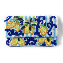 Load image into Gallery viewer, A folded clutch bag featuring a detailed beaded pattern of lemons on a branch with blue scrollwork, set against a light blue and white striped background.