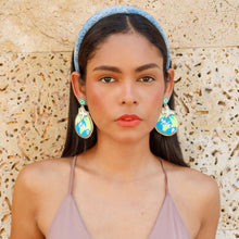 Load image into Gallery viewer, Model wearing blue globe-inspired statement earrings and a denim blue headband against a textured stone wall.