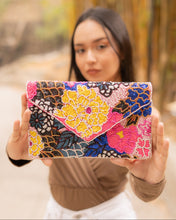 Load image into Gallery viewer, A woman showcasing a vibrant, colorful beaded clutch bag with floral designs.