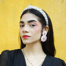 Load image into Gallery viewer, Elegant portrait of a woman wearing a sparkling crystal-embellished headband and pastel floral statement earrings against a vibrant yellow wall.