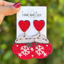 Load image into Gallery viewer, Hand holding a card with red teacups and hearts against a blurred green background