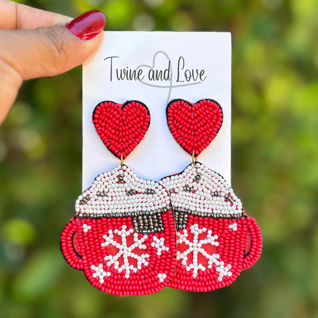 Hand holding a card with red teacups and hearts against a blurred green background
