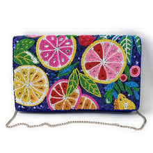 Load image into Gallery viewer, A rectangular clutch bag covered in colorful beaded citrus and leaf patterns on a dark blue background, with a silver chain strap, photographed on a white background.