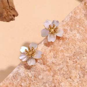 Delicate flower-shaped earrings with white petals and gold center on a white background. They emit an elegant, sophisticated tone.