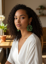 Load image into Gallery viewer, Dangling earrings feature vibrant green gemstones shaped like leaves with a red circular top. A small cluster of white stones accent the bottom. Festive and elegant.