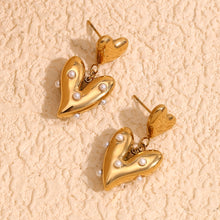 Load image into Gallery viewer, 18k Gold plated heart-shaped earrings with pearl accents on a beige textured background