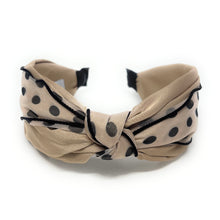 Load image into Gallery viewer, Beige headband with black polka dots, featuring a central knotted twist. The soft fabric and playful design evoke a chic and whimsical tone.