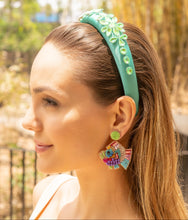 Load image into Gallery viewer, Woman wearing a turquoise headband with floral embellishments and colorful earrings outdoors.