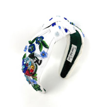 Load image into Gallery viewer, White hand-beaded knotted headband featuring a colorful jeweled bird, blue flowers, green leaves, and sparkling crystal embellishments. Handmade statement hair accessory by Twine and Love.