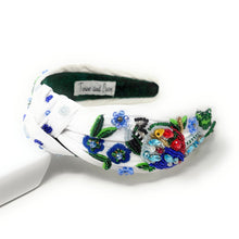 Load image into Gallery viewer, White hand-beaded knotted headband featuring a colorful jeweled bird, blue flowers, green leaves, and sparkling crystal embellishments. Handmade statement hair accessory by Twine and Love.
