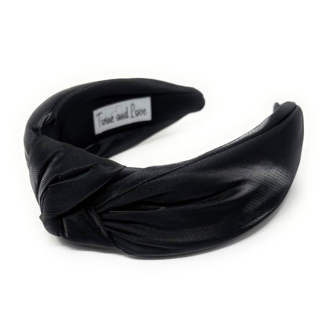 Black satin headband with a knotted design on a white background