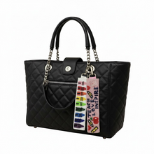 Load image into Gallery viewer, Black quilted handbag with a colorful keychain on a white background
