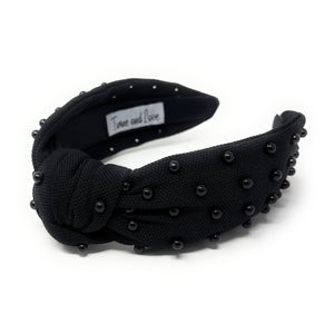Black fabric headband adorned with small black beads, featuring a knotted design in the center. 