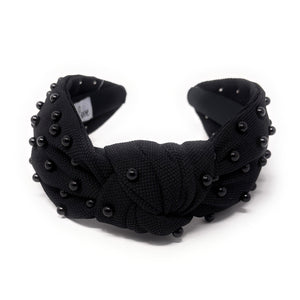 Black fabric headband adorned with small black beads, featuring a knotted design in the center. 