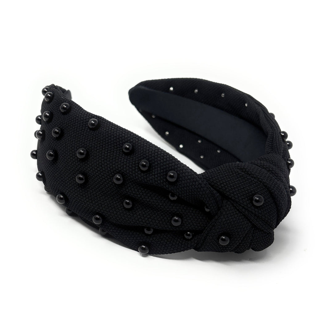Black fabric headband adorned with small black beads, featuring a knotted design in the center. 