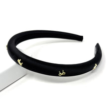 Load image into Gallery viewer, Elegant black satin headband adorned with small gold bow embellishments, displayed against a plain white background, conveying a stylish and chic tone.