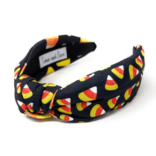 Load image into Gallery viewer, A black headband with colorful candy corn print, featuring white, orange, and yellow. Fun, Halloween-themed accessory.