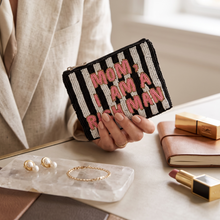 Load image into Gallery viewer, A person in a beige blazer holds a black and white striped beaded pouch with pink text reading 'MOM! I AM A RICH MAN'. The scene is styled on a desk with pearls, a gold bracelet, a notebook, and lipstick.