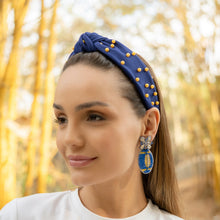 Load image into Gallery viewer, A woman wearing a stylish blue headband with pearls and elegant earrings in a natural setting.