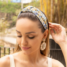 Load image into Gallery viewer, Woman wearing a blue and beige floral knotted headband with statement floral earrings in an outdoor setting.