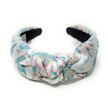 Load image into Gallery viewer, A padded headband with a knot design, featuring a pastel floral pattern in blue, pink, and gold on a white background.