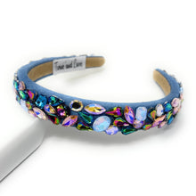 Load image into Gallery viewer, A vibrant, gemstone-encrusted headband with a blue fabric base adorned with multicolored jewels, including blue, purple, and gold, emanating a luxurious and playful vibe.