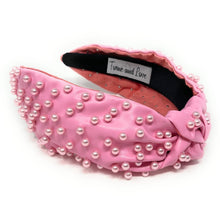 Load image into Gallery viewer, Woman wearing a pink pearl-embellished knotted headband paired with statement earrings, styled with a black ruffled off-the-shoulder top.