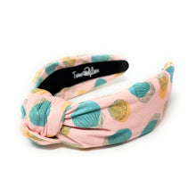 Load image into Gallery viewer, Blush pink knotted headband featuring a pastel seashell print in turquoise, sage green, and golden yellow on textured fabric. Lightweight padded hair accessory perfect for beach vacations, coastal style, and everyday wear by Twine and Love