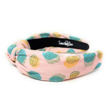 Load image into Gallery viewer, Blush pink knotted headband featuring a pastel seashell print in turquoise, sage green, and golden yellow on textured fabric. Lightweight padded hair accessory perfect for beach vacations, coastal style, and everyday wear by Twine and Love