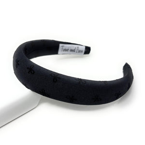 Black headband with bow patterns on a white background