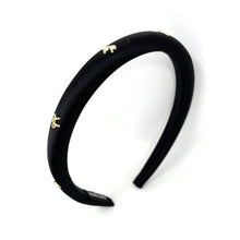 Load image into Gallery viewer, Elegant black satin headband adorned with small gold bow embellishments, displayed against a plain white background, conveying a stylish and chic tone.
