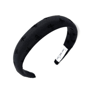 Elegant black fabric headband with subtle bow pattern. Minimalist and chic.