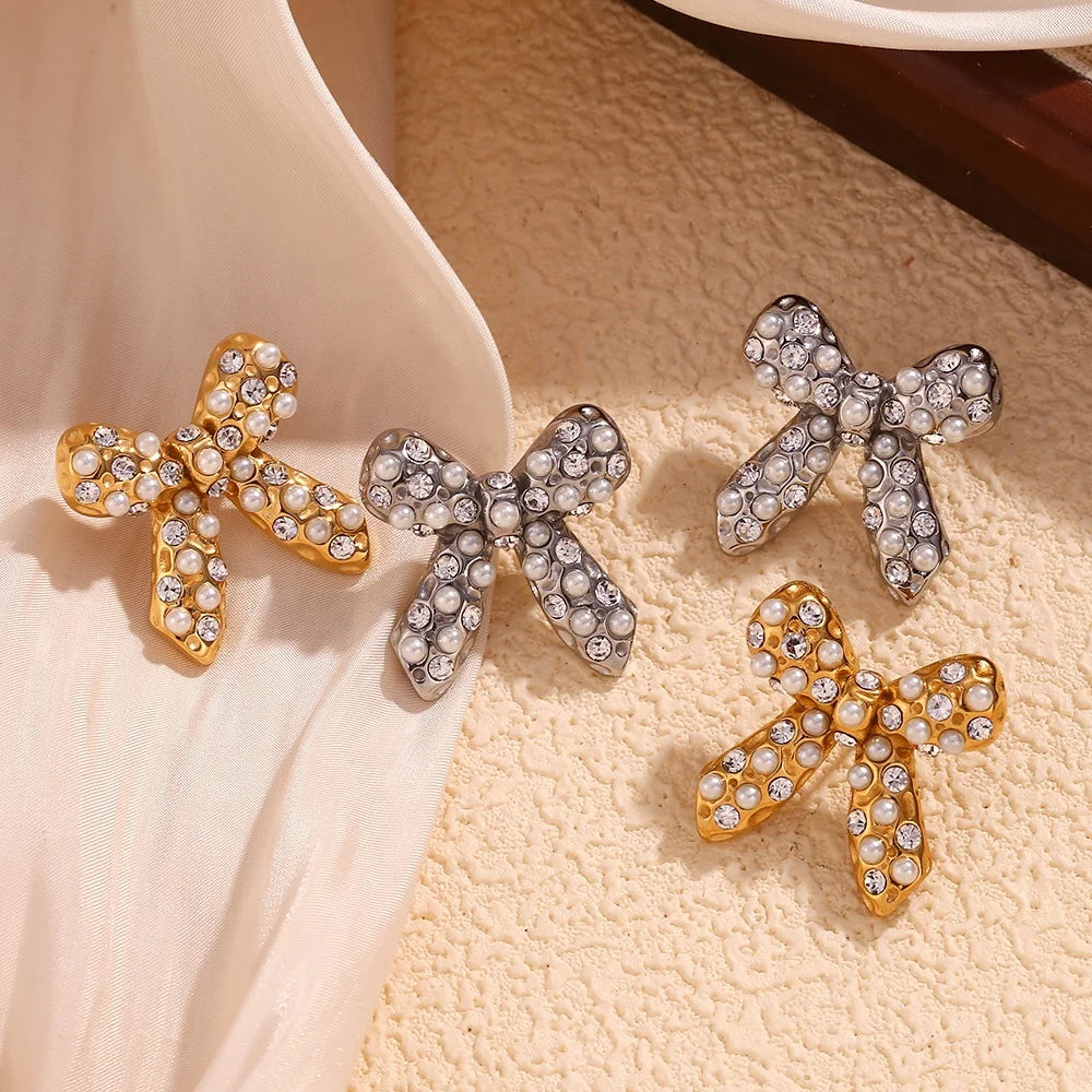 Bow-shaped earrings with rhinestones on a textured surface