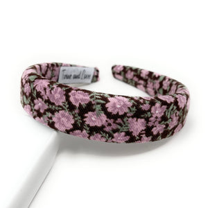 Floral-patterned headband featuring pink and green flowers on a brown background. 