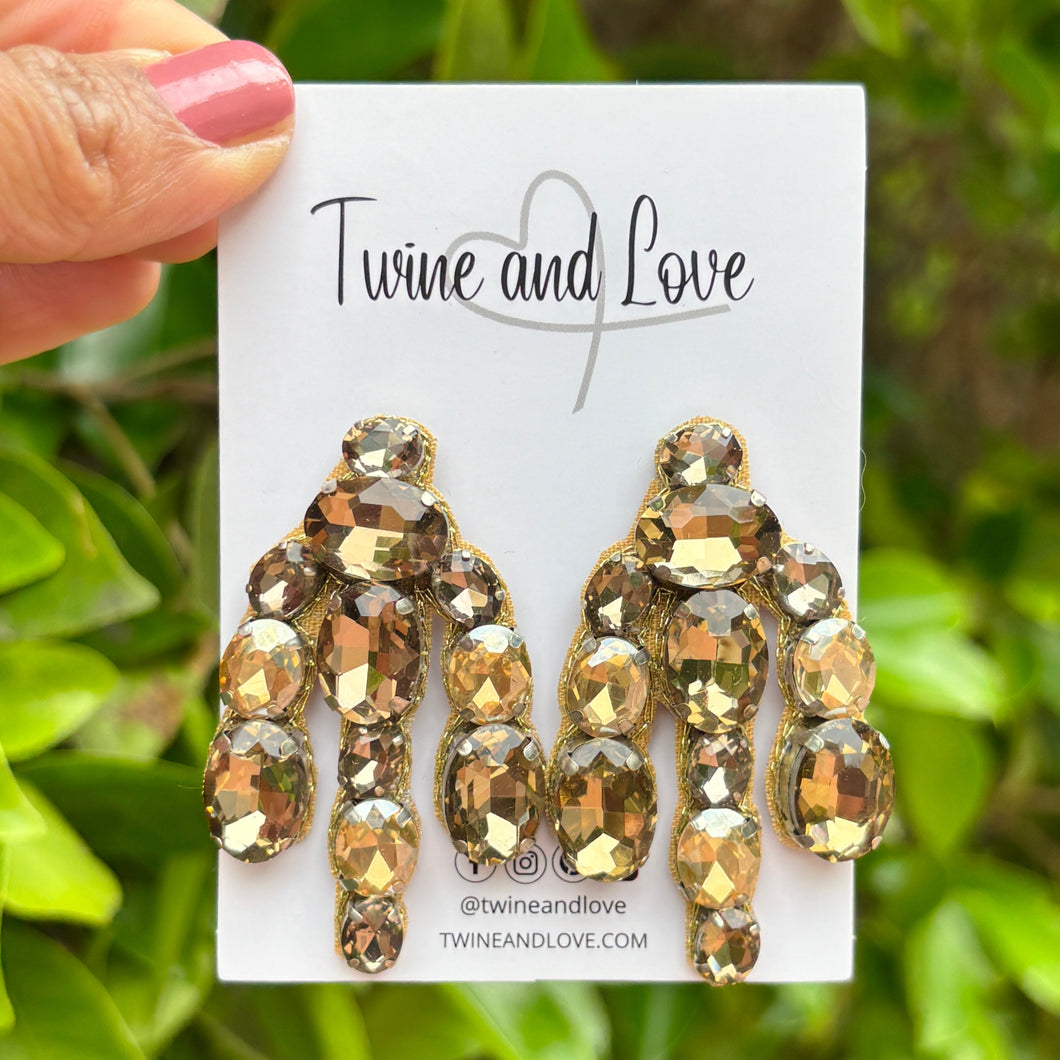 Elegant earrings featuring clusters of brown and champagne-colored gemstones, arranged in a cascading design, conveying a luxurious and sophisticated tone.